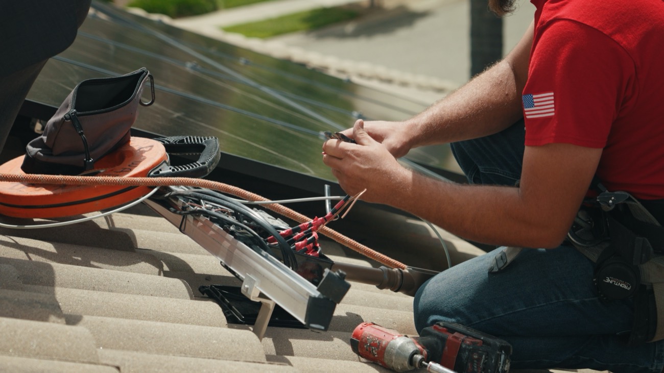 A Westhaven installer wiring a rooftop solar array by hand.